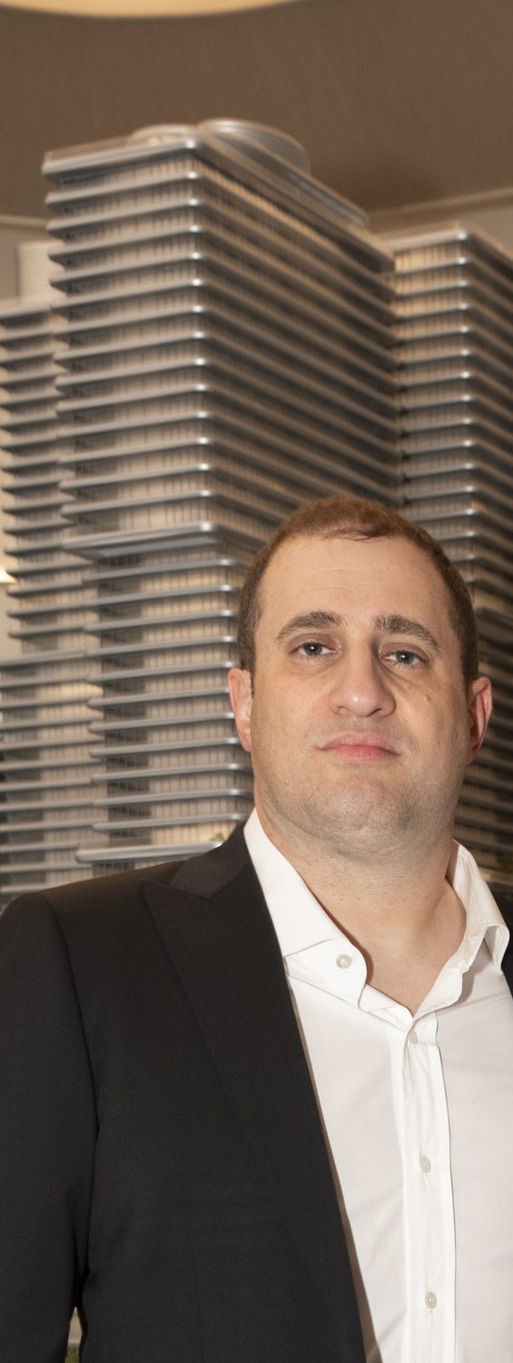Michael Stern photographed beside a detailed architectural model of a terraced tower.